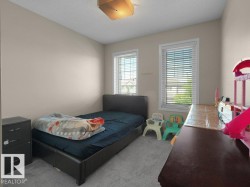 Carpeted interior room with neutral-toned walls, two windows featuring white blinds, and a flush mount ceiling light fixture - 