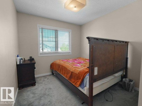 Bedroom featuring neutral wall paint, gray carpeting, a window with blinds, and a ceiling-mounted light fixture - 1419 27 Av, Edmonton, AB 