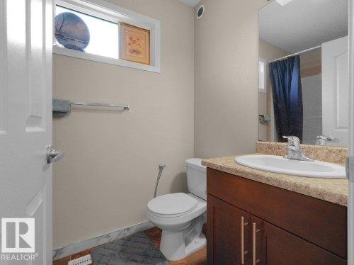 Bathroom featuring a dark wood-finish vanity with a light-toned countertop, undermount sink, and chrome faucet - 1419 27 Av, Edmonton, AB 