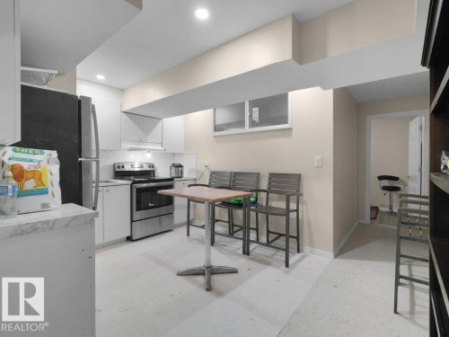 Galley kitchen featuring white cabinetry, stainless steel appliances, and a mosaic tile backsplash - 1419 27 Av, Edmonton, AB 