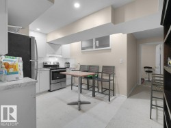 Galley kitchen featuring white cabinetry, stainless steel appliances, and a mosaic tile backsplash - 