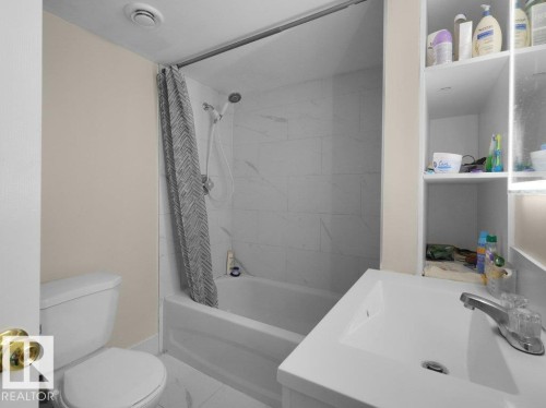 Bathroom featuring a full-size tub and shower combination with white tiled surround - 1419 27 Av, Edmonton, AB 