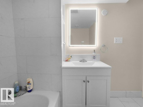 Bathroom vanity featuring a vessel sink, integrated LED mirror, and white cabinetry - 1419 27 Av, Edmonton, AB 