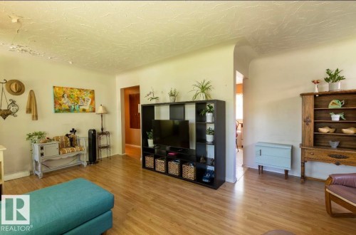 Spacious interior featuring wood-finish flooring, light-toned walls, and arched doorways - 8719 67 Avenue, Edmonton, AB 