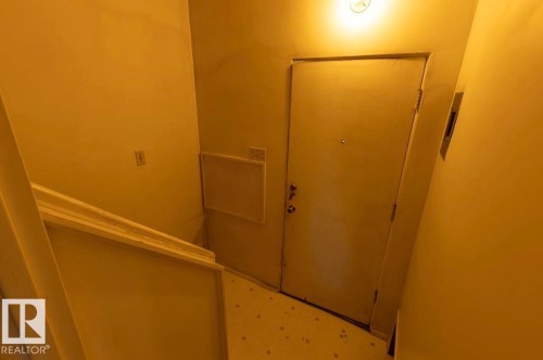 Entry door with multiple locks, ceiling-mounted light fixture, and white floor tiling - 8719 67 Avenue, Edmonton, AB 