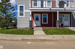 Duplex exterior featuring red and gray horizontal siding, white trim, and a second-story balcony with white railings - 