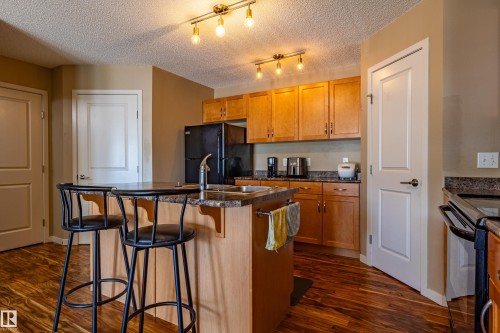 Kitchen featuring wood-finish flooring, light wood cabinetry, and track lighting - 13 1816 Rutherford Road, Edmonton, AB 