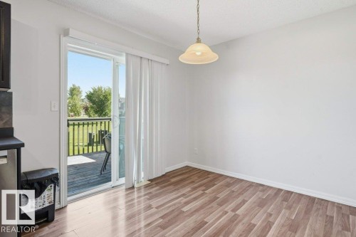Wood-finish flooring throughout, with a sliding glass door providing access to an exterior deck - 30 1404 Hermitage Road, Edmonton, AB 