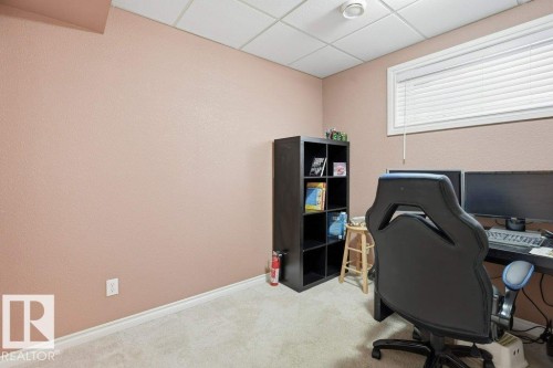 Carpeted room featuring a drop ceiling with recessed lighting, a window with horizontal blinds, and a built-in shelving unit - 30 1404 Hermitage Road, Edmonton, AB 