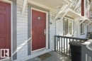 Entry with a rich red paneled door, horizontal siding, and a wooden porch railing - 30 1404 Hermitage Road, Edmonton, AB 