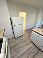 Kitchen area featuring wood-finish flooring, a white refrigerator, and a white dishwasher - 