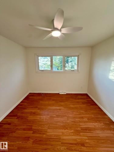 Bright room featuring wood-finish flooring, a contemporary ceiling fan with integrated lighting, and white baseboards - 10220 107 Street, Westlock, AB - Indoor Photo Showing Other Room