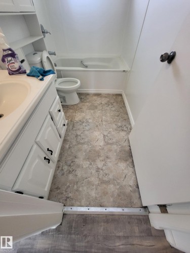 Bathroom featuring a white bathtub with chrome fixtures, a toilet, and a white vanity with paneled doors and black hardware - 10220 107 Street, Westlock, AB - Indoor Photo Showing Bathroom