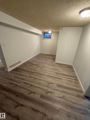 Spacious room featuring wood-finish flooring, white baseboards, and neutral wall paint - 10220 107 Street, Westlock, AB - Indoor