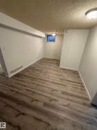 Spacious room featuring wood-finish flooring, white baseboards, and neutral wall paint - 