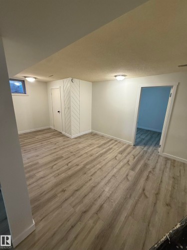 Spacious room featuring wood-finish flooring, white walls, and flush-mount ceiling lighting - 10220 107 Street, Westlock, AB - Indoor