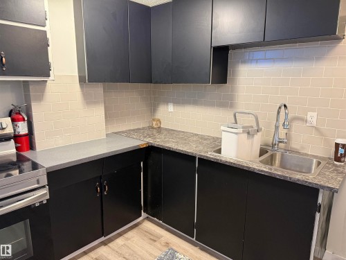 Kitchen featuring dark cabinetry, light-toned subway tile backsplash, and composite countertops - 10220 107 Street, Westlock, AB - Indoor Photo Showing Kitchen With Double Sink