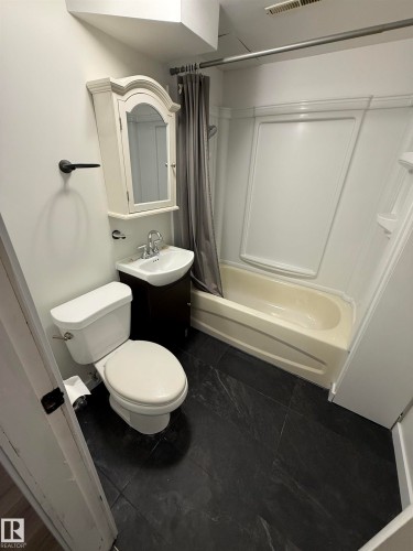 Bathroom featuring dark slate-look flooring, a white toilet, and a vanity with an integrated sink - 10220 107 Street, Westlock, AB - Indoor Photo Showing Bathroom
