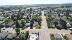 Aerial perspective of a developed residential area featuring tree-lined streets and established homes - 
