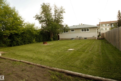 Expansive backyard featuring a manicured lawn, established perimeter trees, and a wood privacy fence - 10220 107 Street, Westlock, AB - Outdoor