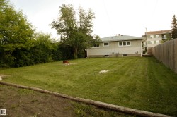Expansive backyard featuring a manicured lawn, established perimeter trees, and a wood privacy fence - 