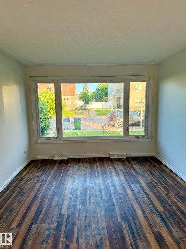 Spacious interior featuring wood-finish flooring and a wide picture window - 10220 107 Street, Westlock, AB - Indoor Photo Showing Other Room