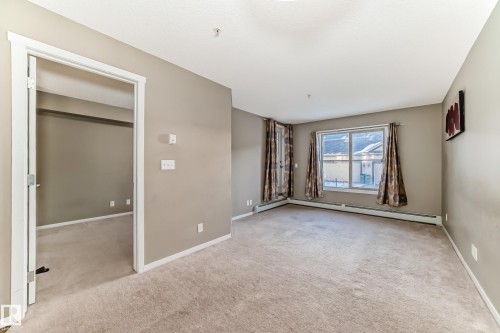 Neutral-toned room with plush carpeting and a large window - 121 111 Watt Common, Edmonton, AB 