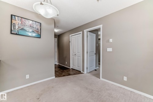 Carpeted flooring extending into a hallway with contrasting dark tile - 121 111 Watt Common, Edmonton, AB 