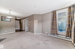 Carpeted living area featuring a large window, neutral paint colors, and a ceiling-mounted light fixture - 