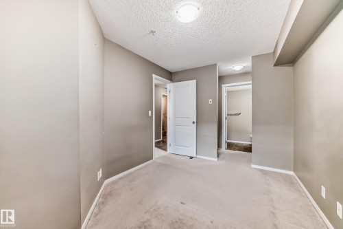 Carpeted room featuring a neutral paint palette, two interior doors, and overhead flush mount lighting - 121 111 Watt Common, Edmonton, AB 