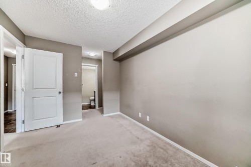 Carpeted room with neutral-toned walls, white baseboards, and a textured ceiling - 121 111 Watt Common, Edmonton, AB 
