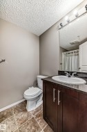 Bathroom vanity with dark wood-finish cabinetry, an oval undermount sink, and a dark stone-look countertop - 