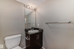 Bathroom featuring a dark wood-finish vanity with an integrated sink, dark countertop, and brushed nickel hardware - 