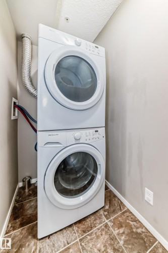 Dedicated laundry area featuring a stacked washer and dryer unit - 121 111 Watt Common, Edmonton, AB 