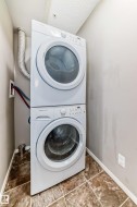 Dedicated laundry area featuring a stacked washer and dryer unit - 