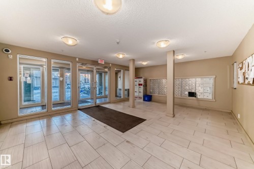 Building entryway featuring light-toned rectangular floor tiles, multiple wall-mounted mailboxes, and neutral-colored walls - 121 111 Watt Common, Edmonton, AB 