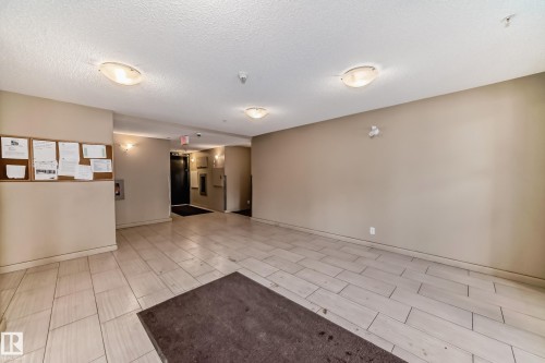 Building entryway featuring light-toned tile flooring, neutral wall paint, and flush-mount ceiling lighting - 121 111 Watt Common, Edmonton, AB 