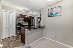 Kitchen featuring dark wood cabinetry, stainless steel appliances, and a black countertop island - 