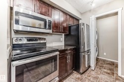 Kitchen featuring stainless steel appliances, dark wood cabinetry, and a stacked washer and dryer unit - 