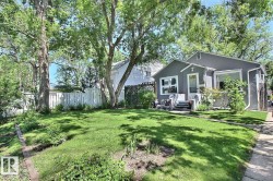 Gray stucco exterior featuring a front entrance with white trim, a large picture window, and a concrete pathway - 