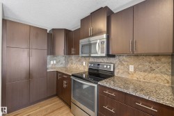 Kitchen featuring wood-finish cabinetry, granite-style countertops, stainless steel appliances, a built-in microwave, and a tiled backsplash - 