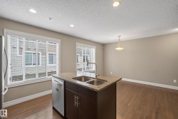 Kitchen island featuring a double basin stainless steel sink, gooseneck faucet, and stone countertop - 