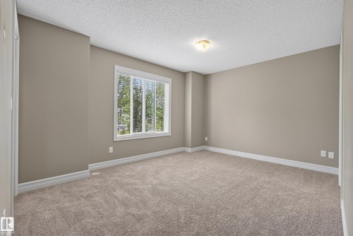 Spacious room featuring neutral carpeting, light neutral wall paint, and white baseboards - 53 3625 144 Avenue, Edmonton, AB 