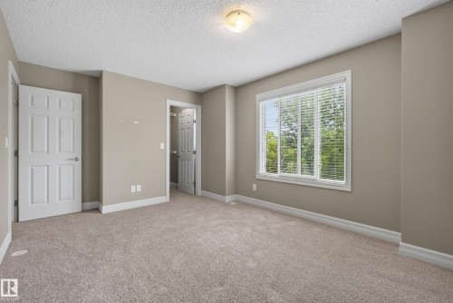 Spacious room with plush carpeting, neutral wall tones, white trim, and a large window with blinds - 53 3625 144 Avenue, Edmonton, AB 