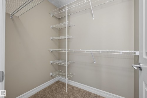 Walk-in closet featuring wire shelving, wire hanging rods, and neutral-toned carpet flooring - 53 3625 144 Avenue, Edmonton, AB 