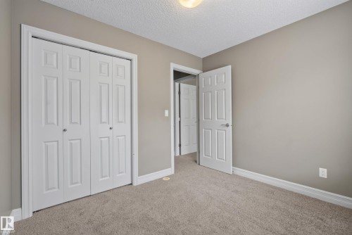 Neutral-toned room featuring a textured ceiling, plush carpet flooring, and white baseboards - 53 3625 144 Avenue, Edmonton, AB 