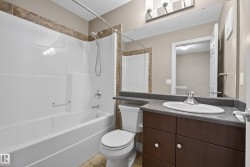 Bathroom featuring a dark wood-finish vanity with a white oval undermount sink, a dark countertop, and a large wall-mounted mirror - 