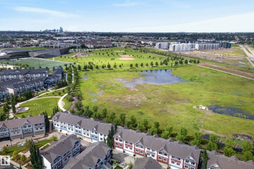 Expansive green space featuring a large central field, natural water features, and surrounding residential structures - 53 3625 144 Avenue, Edmonton, AB 