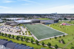 Expansive outdoor sports field with artificial turf, surrounded by green parkland - 