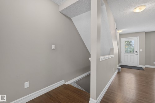 Foyer entry with wood-finish flooring, white paneled door with glass insert, and neutral wall tones - 53 3625 144 Avenue, Edmonton, AB 
